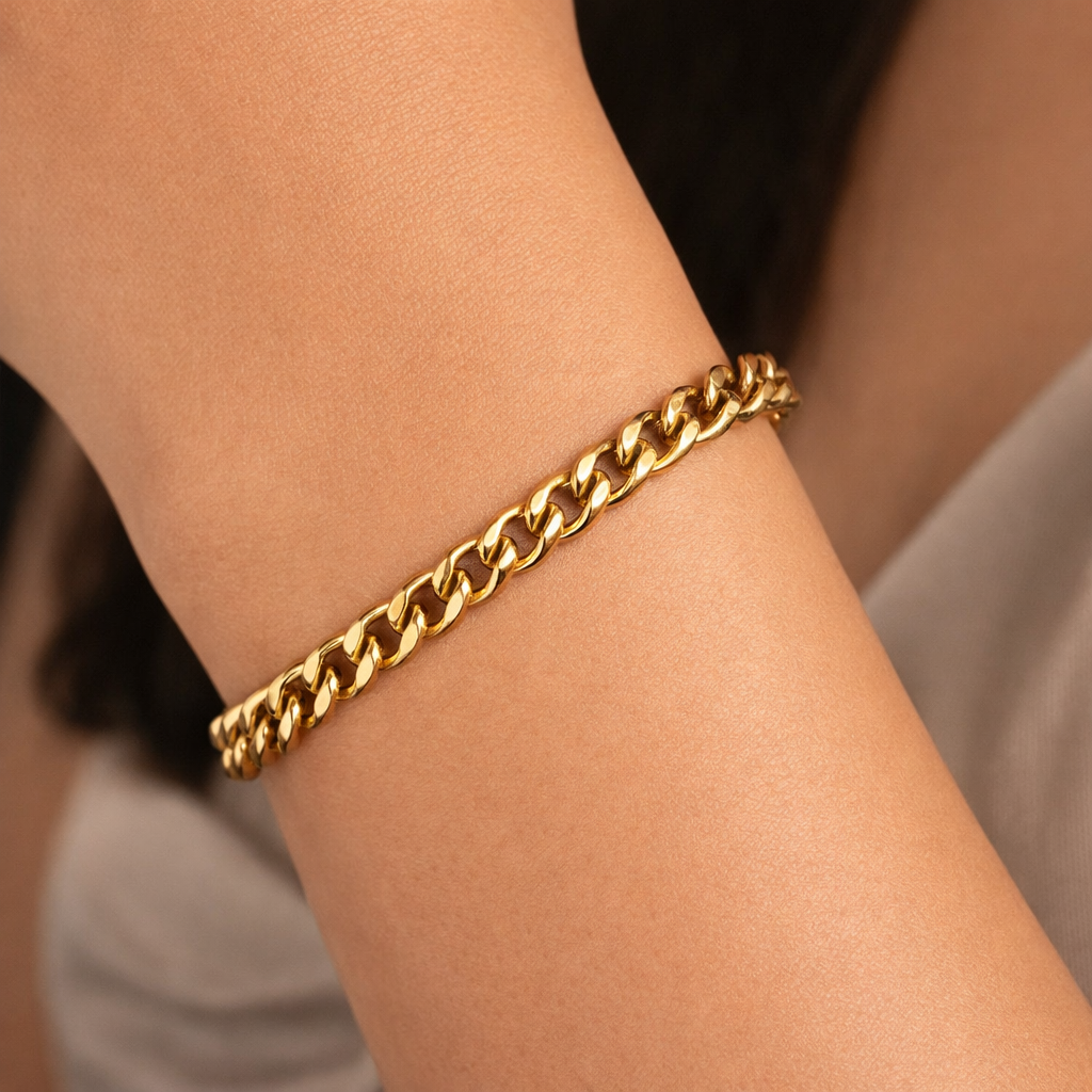 Gold tone chain bracelet on a wrist with a blurred background