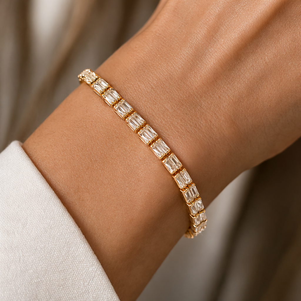 Gold tone bracelet with clear stones on a wrist against a neutral background