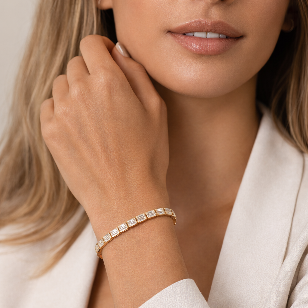 Close-up of a woman wearing a gold tone bracelet with a neutral background