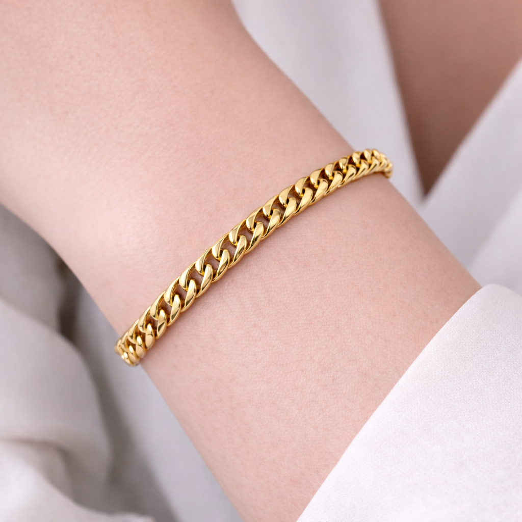 Gold chain bracelet on a person's wrist with a light background