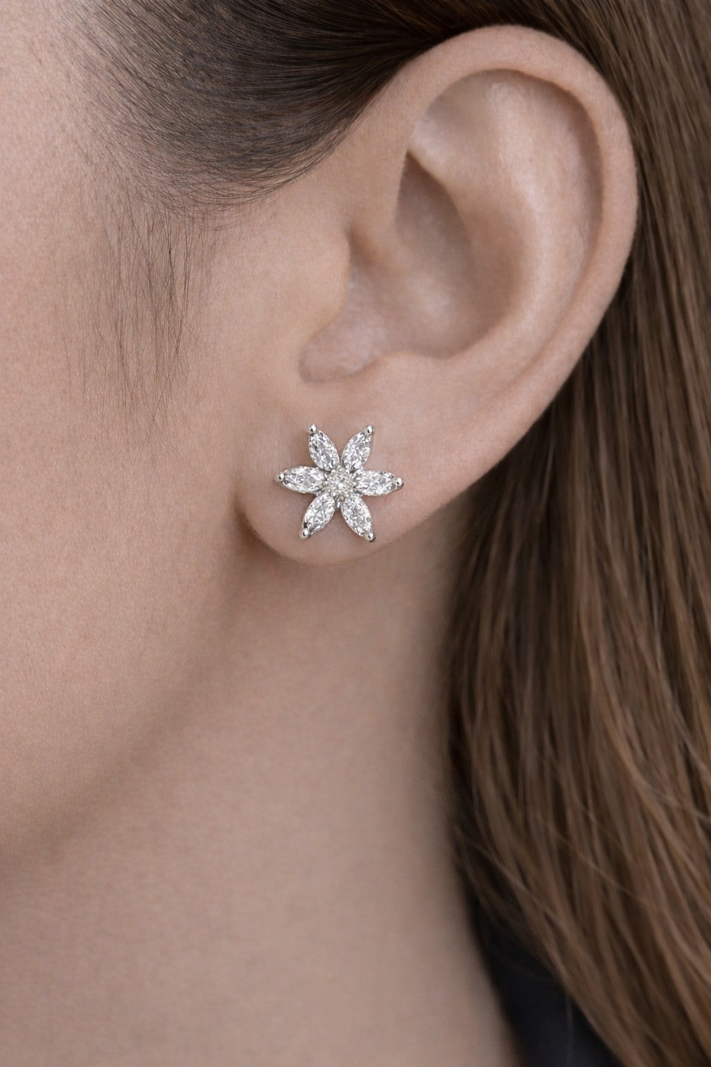 Close-up of an ear wearing a star-shaped clear earring.