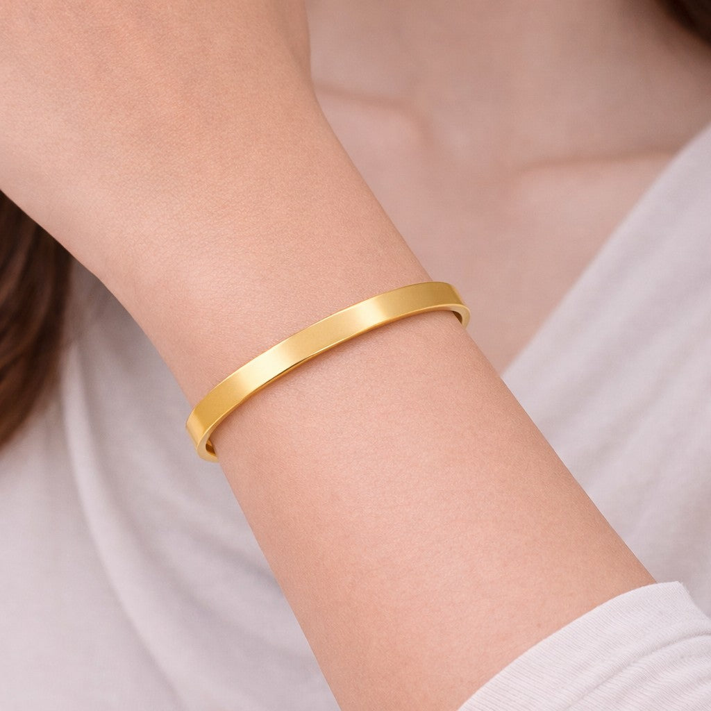 Gold-tone bangles with polished minimal cuff shape on wrist