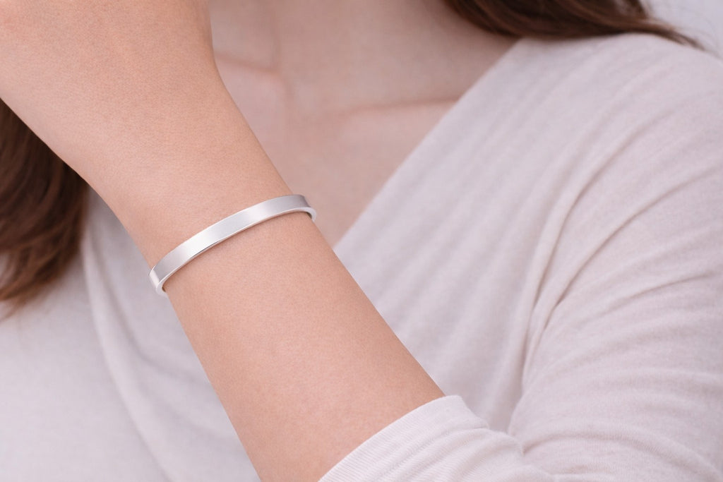 Side view of silver-tone metal bangles with open cuff shape