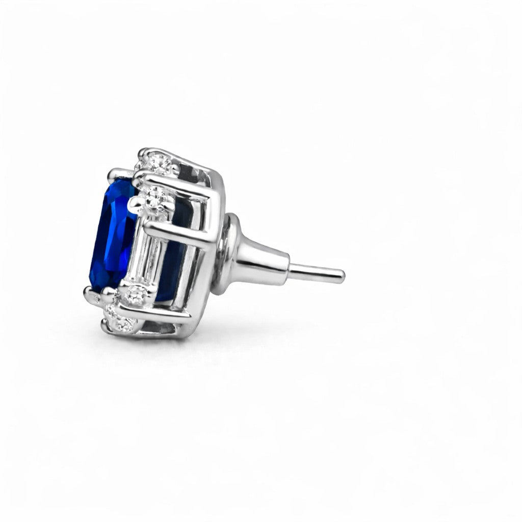 Silver earring with blue gemstone and clear stones on a white background