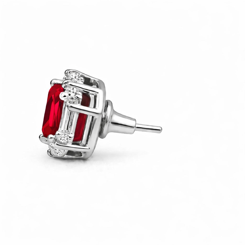 Silver earring with red gemstone and clear stones on a white background