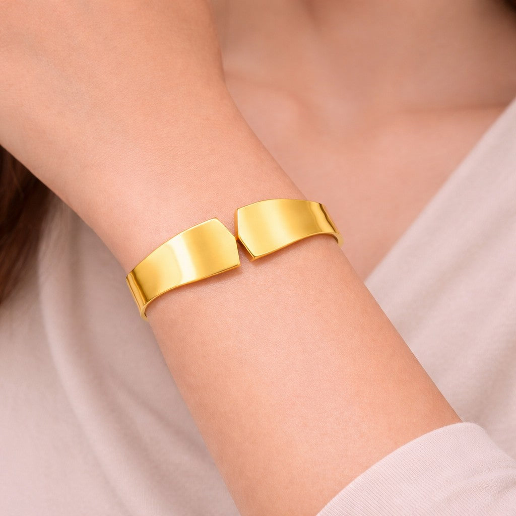 Close-up of gold-tone bangles styled on wrist with smooth polished finish