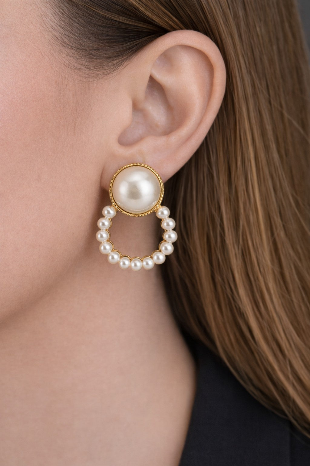 Close-up of gold earrings for women with pearl-studded drop design