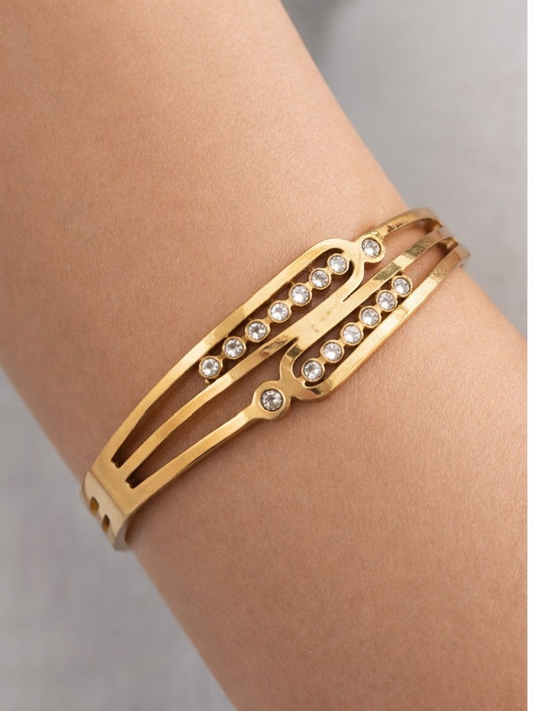 Close-up of artificial bangles with gold-tone cuff design and stone detail on wrist