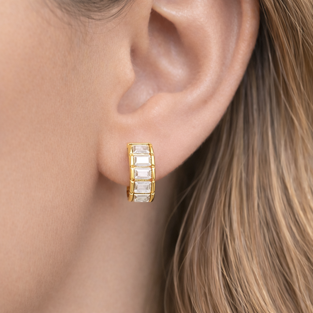 Gold hoop earring with clear stones worn by a person