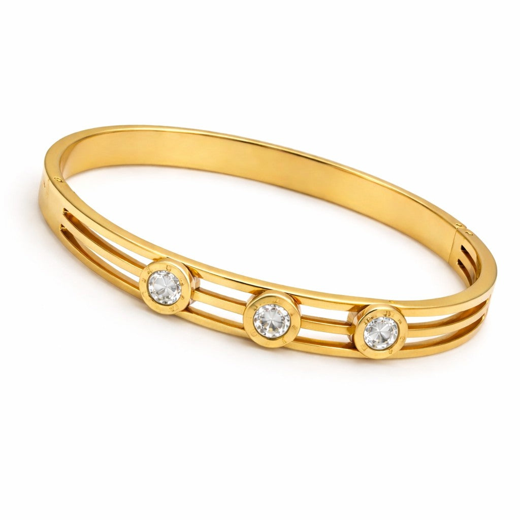 Angled view of bangles for women with polished gold-tone finish and three stones