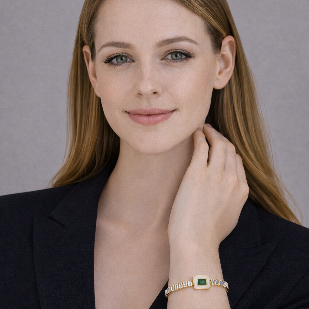 Woman wearing a gold bracelet with a green gemstone against a neutral background