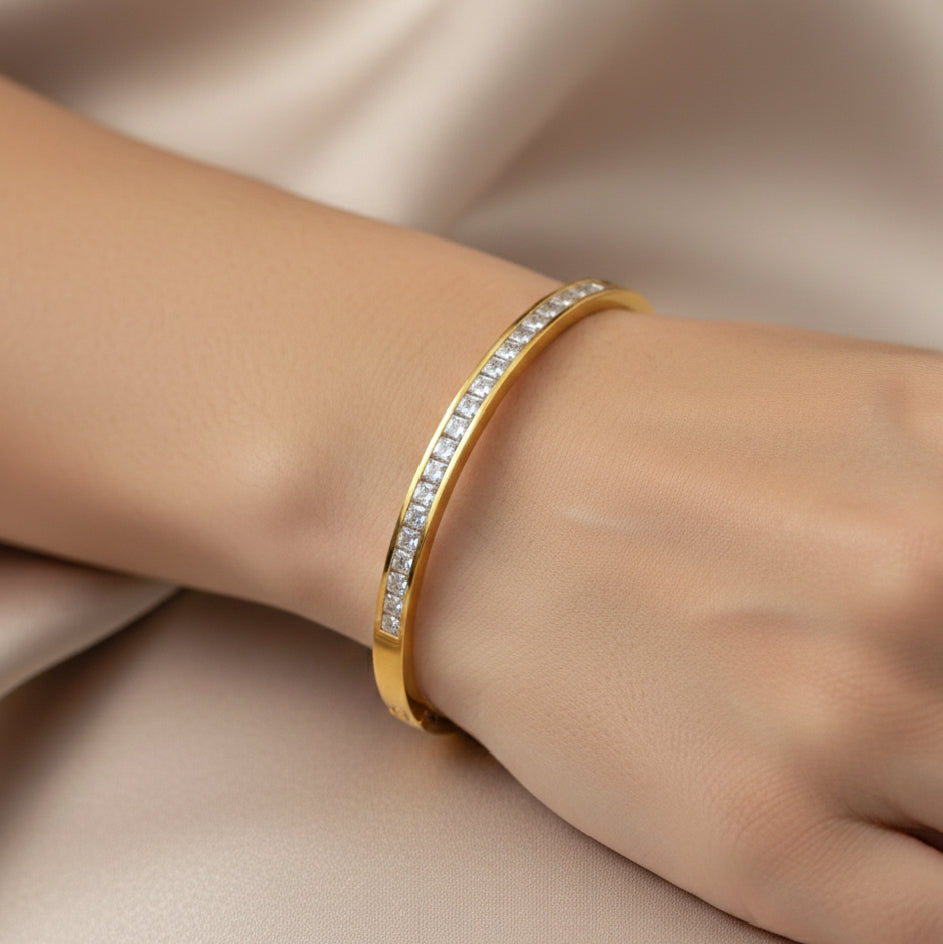 Close-up of stone bangle styled on wrist in a slim gold-tone finish